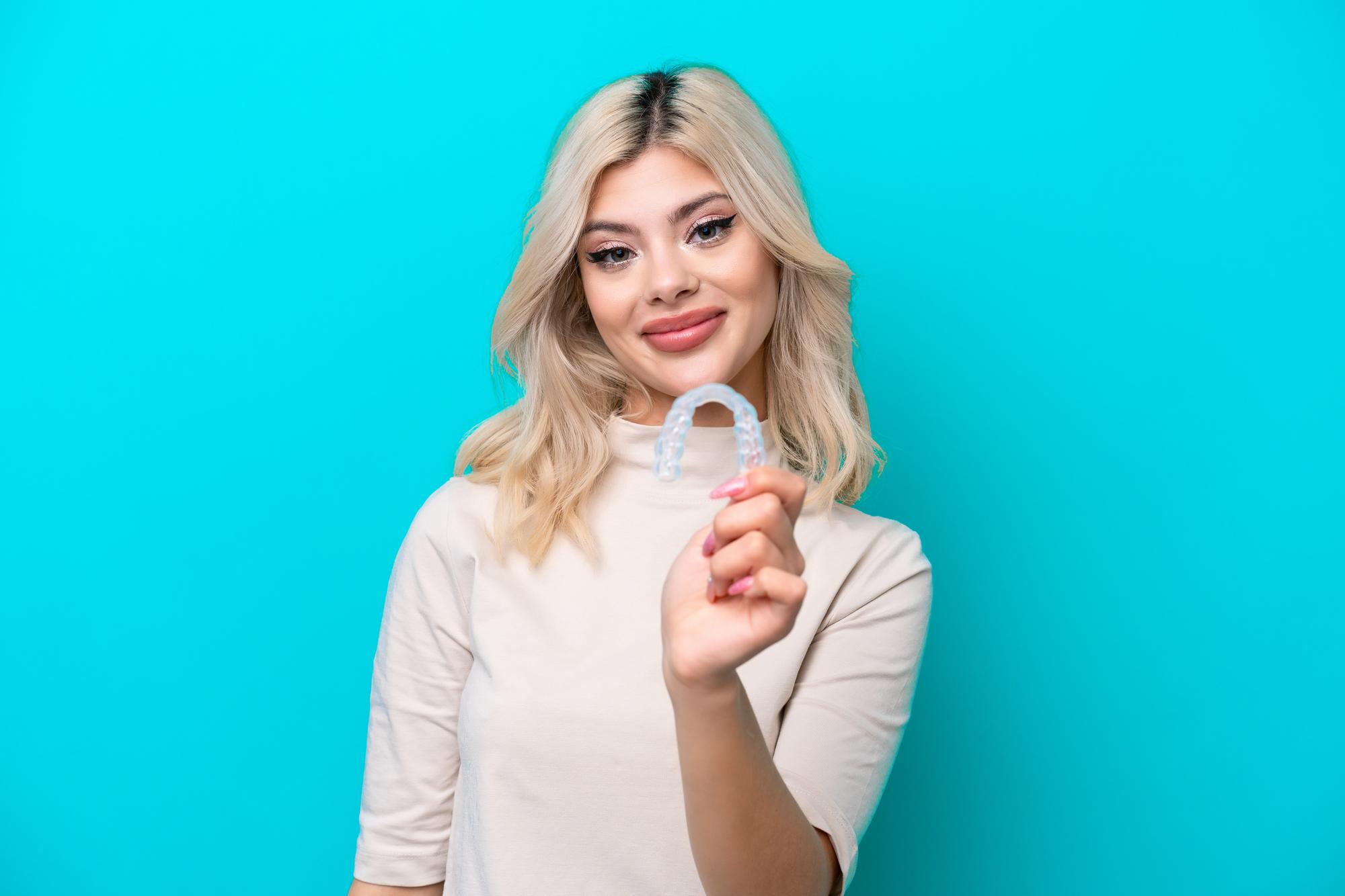 Patient holding a clear Invisalign aligner